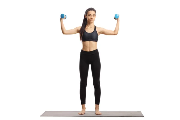 Young woman exercising with dumbbells on an exercise mat — Stockfoto
