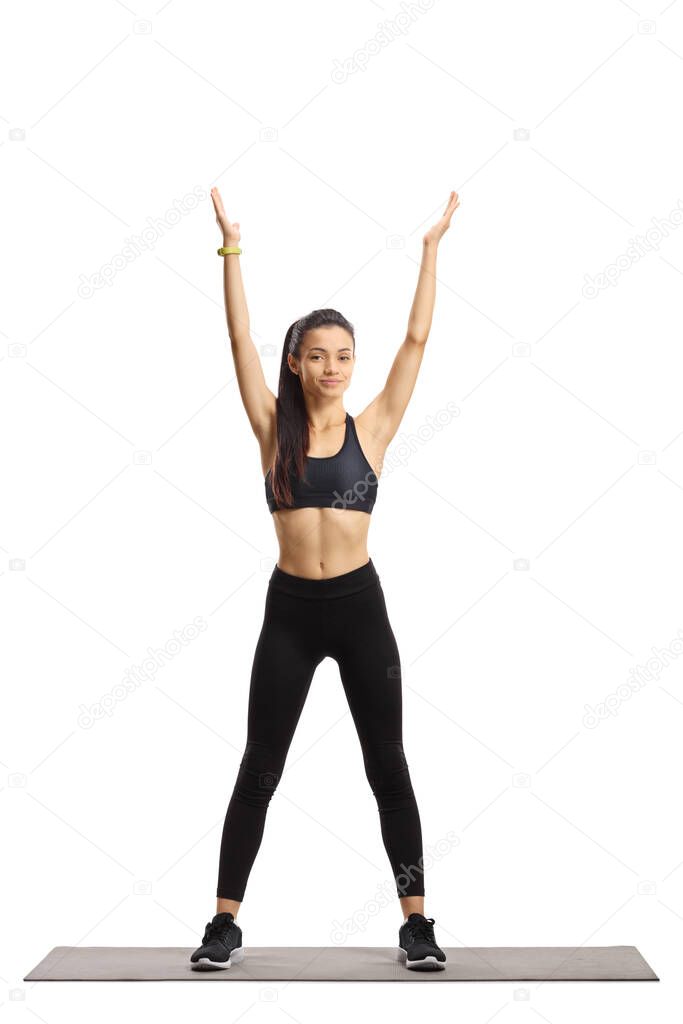 Young female in black top and leggings exercising with raised ar