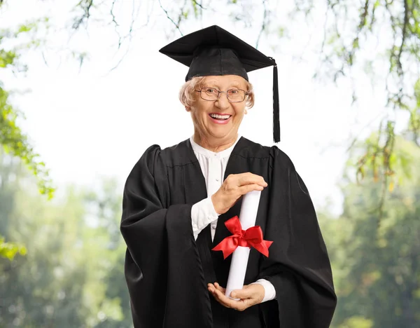 Maturantka v maturitní róbě s pozinem z diplomů — Stock fotografie