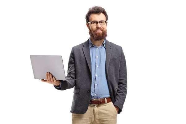Uomo barbuto in piedi con un computer portatile e sorridente alla fotocamera — Foto Stock