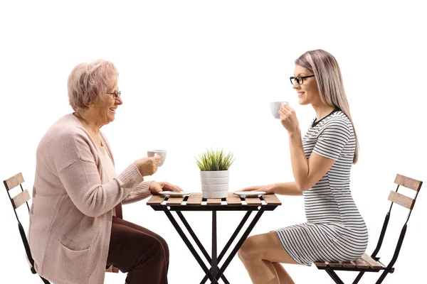 Starší žena pije kávu s mladou ženou u stolu — Stock fotografie