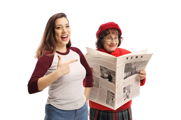 Giovane femmina ridendo e indicando una donna anziana leggere un n — Foto Stock