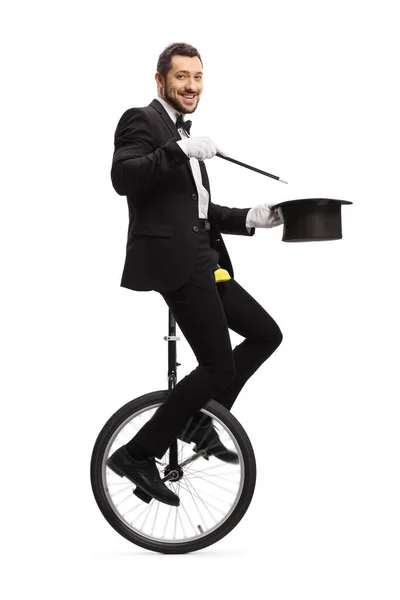 Magician with a wand riding a unicycle and smiling at camera — Stockfoto