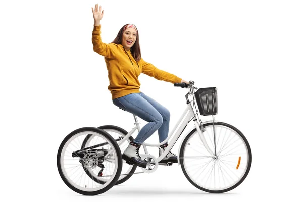 Cheerful young female riding a tricycle and waving at the camera — Stock Photo, Image