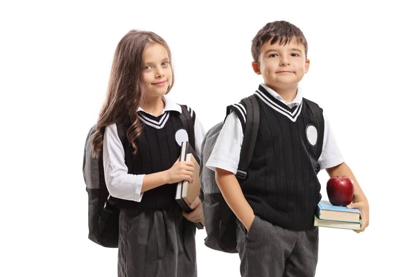 Schoolgirl and schoolboy in a uniform holding books and looking — Stok fotoğraf