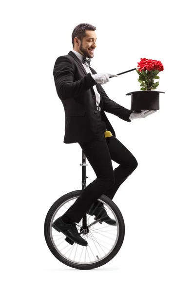 Magician performing on a unicycle with a magic wand, hat and red — Stok fotoğraf