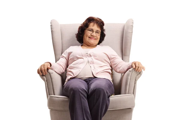Volwassen vrouw glimlachen en zitten in een fauteuil — Stockfoto