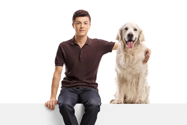 Jovem sentado em um painel e abraçando um cão retriever — Fotografia de Stock