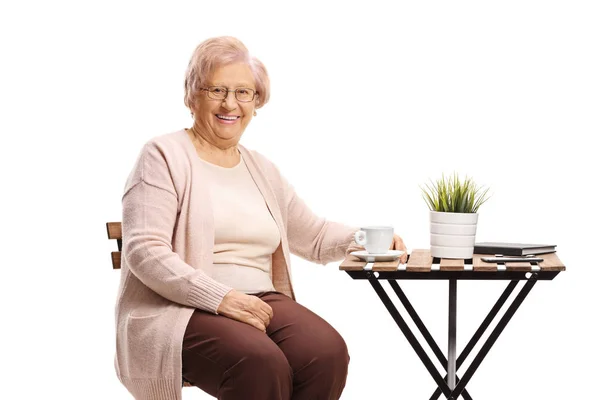Femme âgée assise à une table avec une tasse de café — Photo