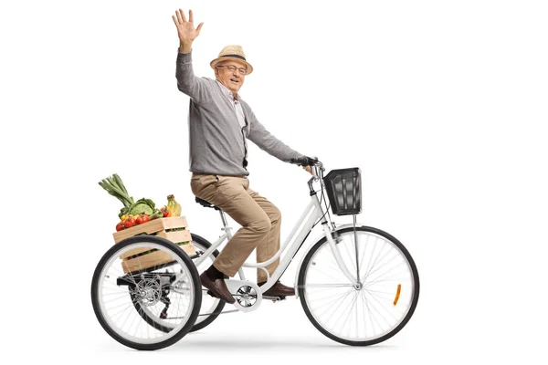 Anciano montando un triciclo con una caja llena de frutas y — Foto de Stock