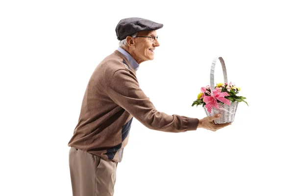 Elderly man giving a basket with flowers — Stock Photo, Image