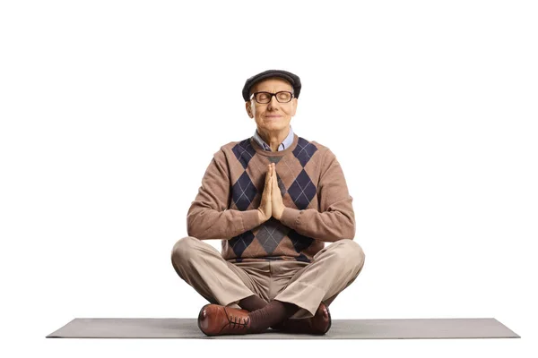 Elderly man sitting on a mat and practicing a yoga pose — Stock Photo, Image