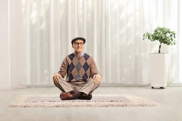 Uomo anziano seduto sul pavimento e meditare — Foto Stock