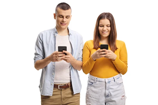Jeune homme et femme debout et tapant sur les téléphones mobiles — Photo