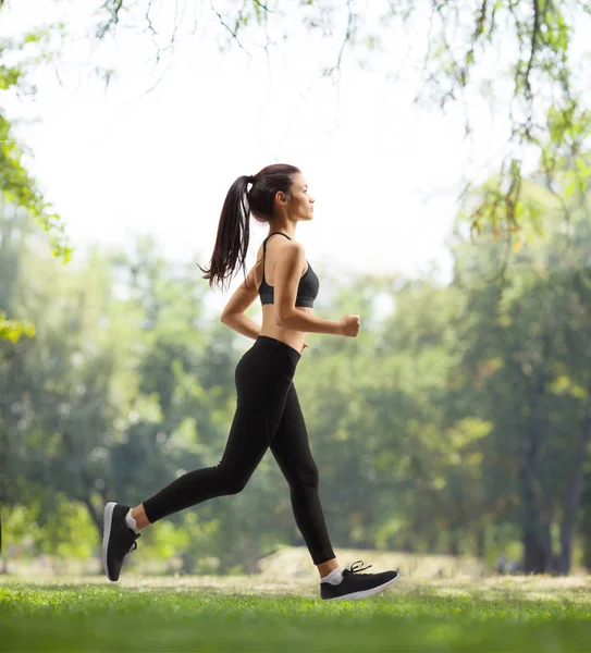 Ung kvinna jogging i en park — Stockfoto