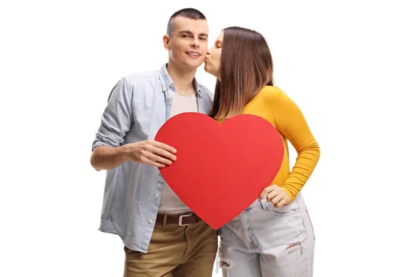 Jovem mulher beijando um cara segurando um grande coração vermelho — Fotografia de Stock