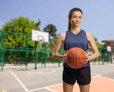 Young woman with a basketball on an outdoor basketball court