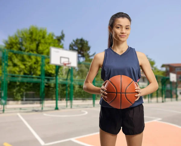 Junge Frau mit einem Basketball auf einem Basketballfeld im Freien — Stockfoto