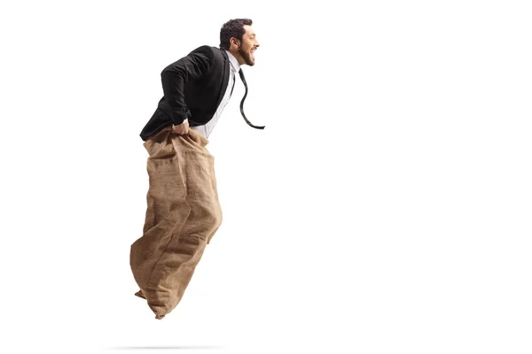 Man in a suit playing a game with jumping in a sack — Stockfoto