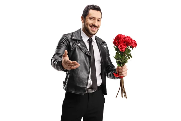 Handsome smiling guy holding red roses and inviting with hand — ストック写真