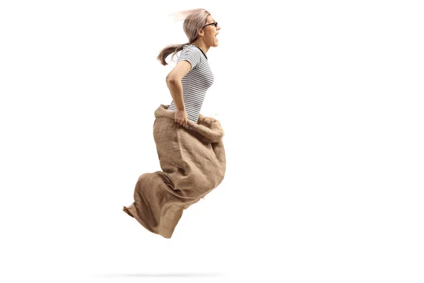 Excited young woman jumping in a sack — Stock Photo, Image