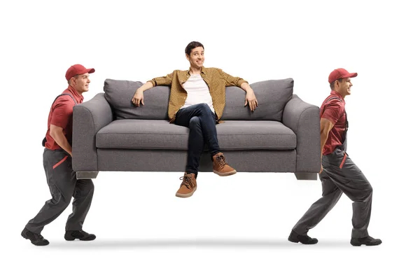 白い背景に孤立して座っている若い男とソファを持っている移動会社から2人の労働者 — ストック写真
