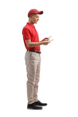 Üniformalı bir kasiyerin beyaz arka planda izole edilmiş paraları saydığı uzun bir çekim.