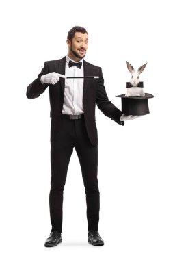 Full length portrait of a magician performing a trick with a hat and a rabbit isolated on white background clipart