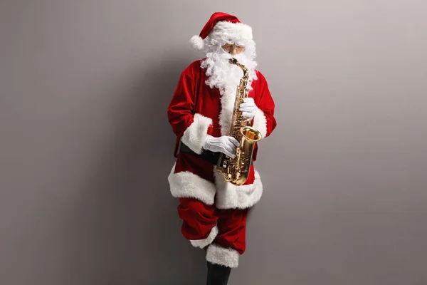 Papai Noel Tocando Saxofone Inclinando Uma Parede Cinza Claro — Fotografia de Stock