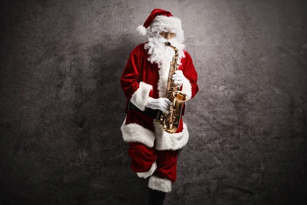 Papai Noel Tocando Saxofone Apoiando Uma Parede Cinza Enferrujada — Fotografia de Stock