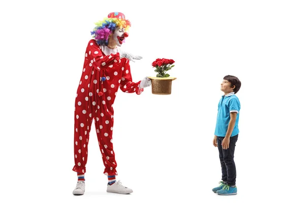 一个小丑在一个被白色背景隔离的男孩面前表演花冠戏法的全景镜头 — 图库照片