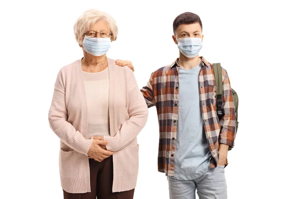 白い背景に隔離された保護顔のマスクを持つ祖母と十代の孫 — ストック写真
