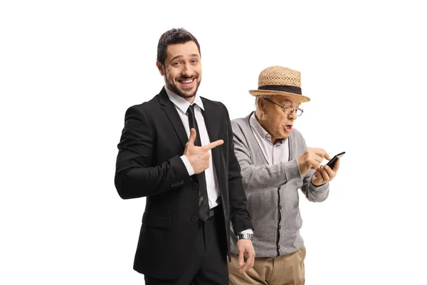 Ung Man Kostym Skrattar Och Pekar Äldre Man Med Mobiltelefon — Stockfoto