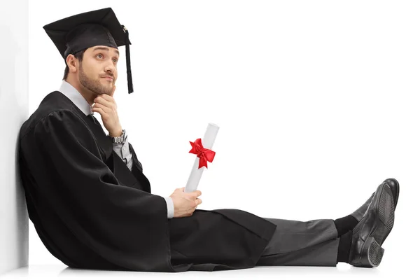 Pensive Graduate Male Student Holding Diploma Sitting Floor Leaning Wall — Stock fotografie