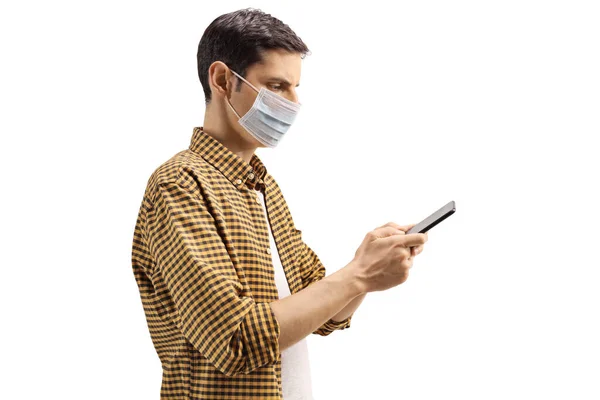 一名戴着防护医疗面罩的年轻人在白色背景下被隔离的手机上打字的照片 — 图库照片