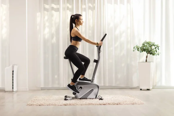 Young Woman Riding Stationary Bike Home — Stock Photo, Image