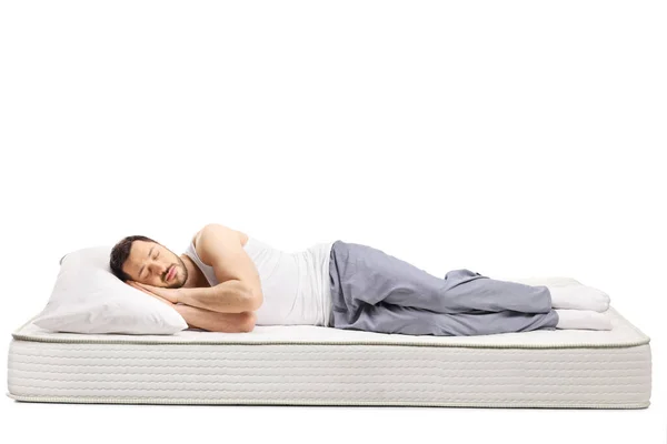 Genç Adam Beyaz Arka Planda Izole Edilmiş Konforlu Bir Yatakta — Stok fotoğraf