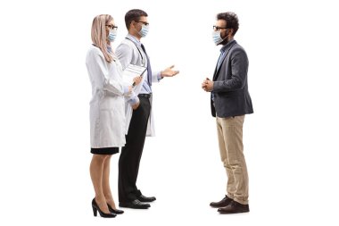 Kadın ve erkek doktorların koruyucu maskeler taktığı ve beyaz arka planda maskeli bir adamla konuştuğu uzun metrajlı bir çekim.