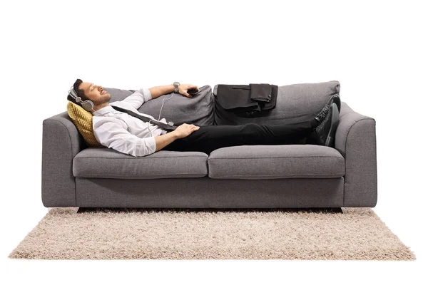 一个穿着正装的男人躺在沙发上 听着独立于白色背景的音乐的全景镜头 — 图库照片