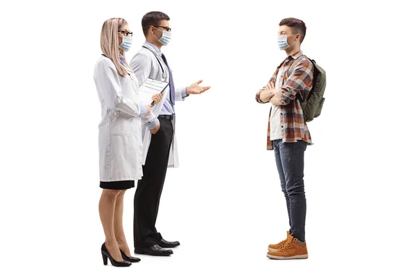 一名戴着口罩的男医生和女医生与一名因白人背景而被隔离的年轻男性病人交谈时的全景照片 — 图库照片