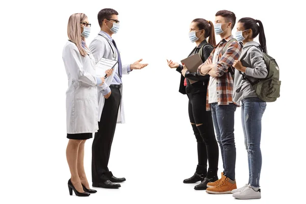 一名戴着口罩的男医生和女医生与一群因白人背景而被隔离的学生讨论的全景照片 — 图库照片