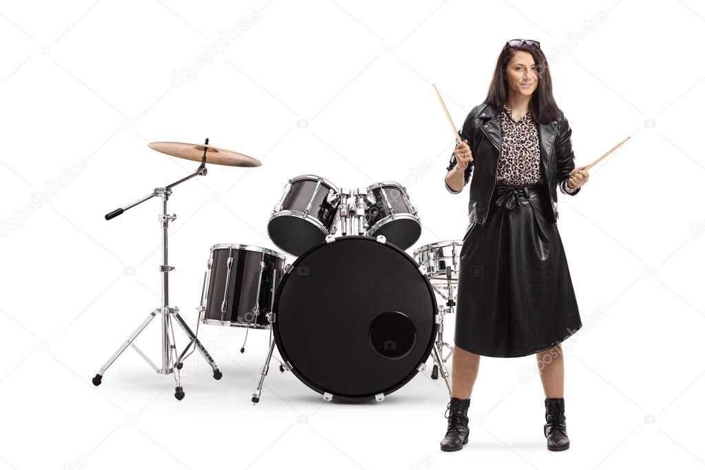 Full length portrait of a young woman drummer with drumsticks with a drum set isolated on white background