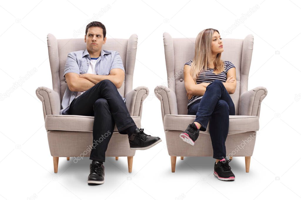 Angry young man and woman sitting in armchairs looking to the side isolated on white background
