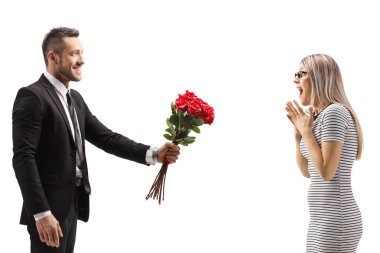 Adam beyaz arka planda yalnız kalmış, şaşırmış bir kadına bir demet kırmızı gül veriyor.