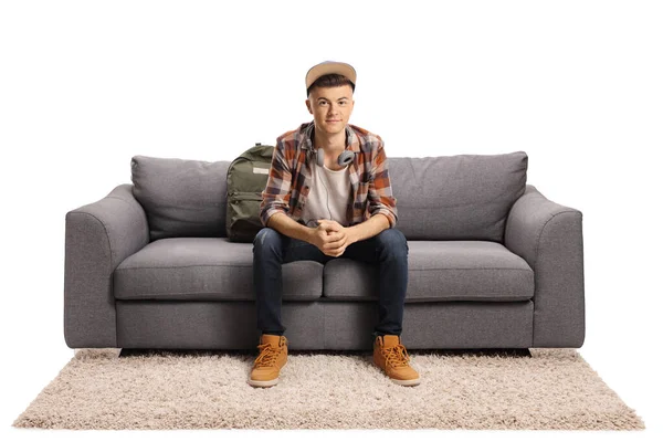 男生坐在沙发上 耳机与白色背景隔离 — 图库照片