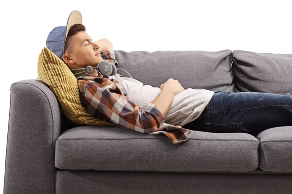 男生躺在沙发上 耳机与白色背景隔离 — 图库照片