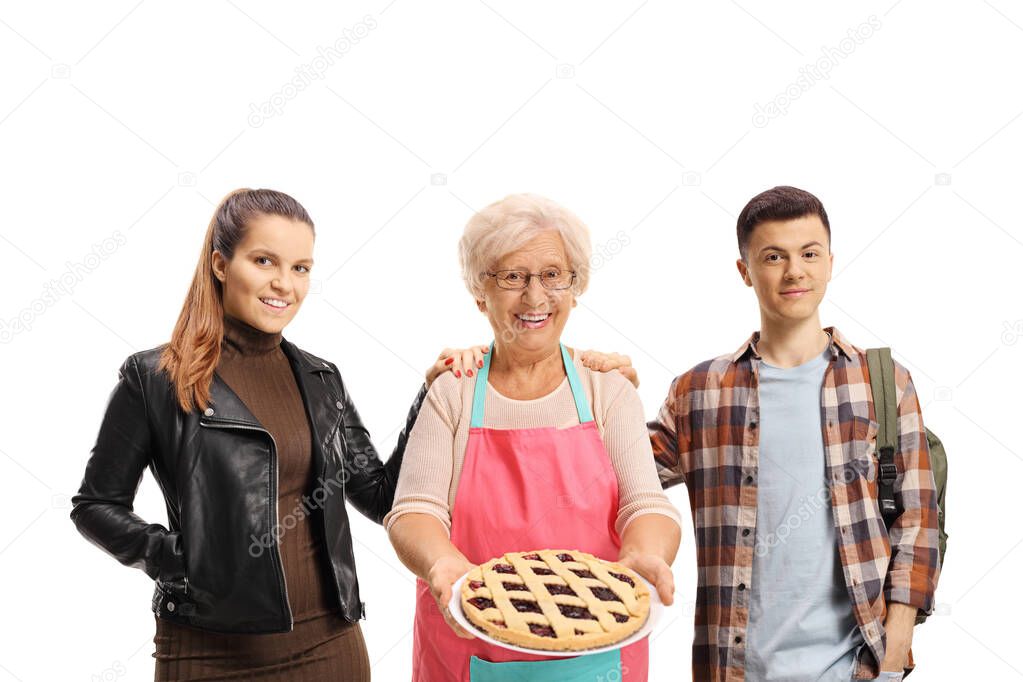 Young female and male standing next to an elderly woman holding a pie isolated on white background