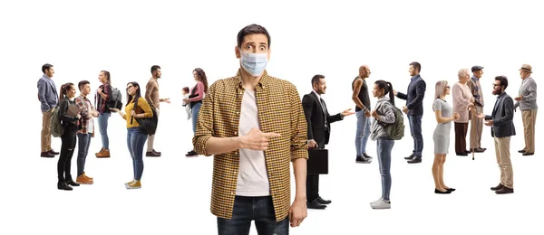 你这个戴着医疗面罩的男人很担心 他指着一大群在白人背景下孤立无援地说话的人 — 图库照片