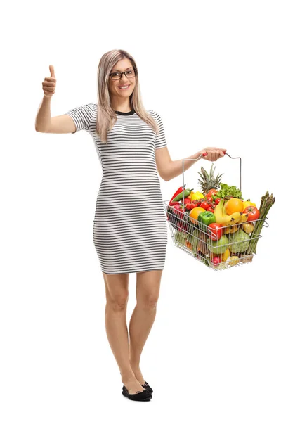白い背景に親指を立て 果物や野菜を入れたショッピングバスケットを持つ若い女性の完全な長さの肖像画 — ストック写真