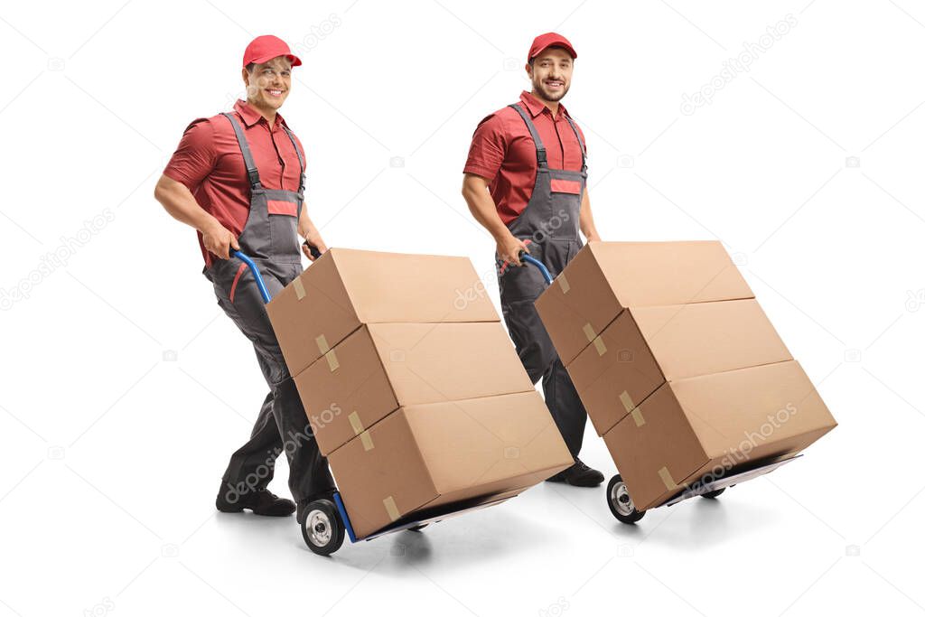Two workers with hand trucks with boxes looking at the camera and smiling isolated on white background